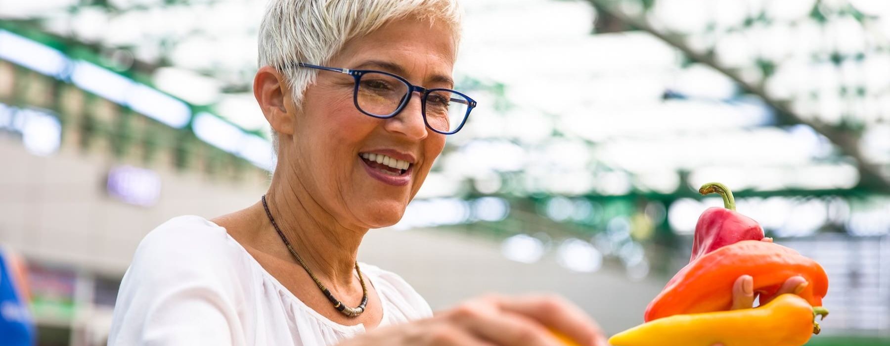 a woman smiling and holding a bunch of vegetables